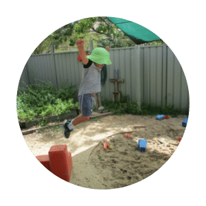 child-jumping-from-block-into-sandpit